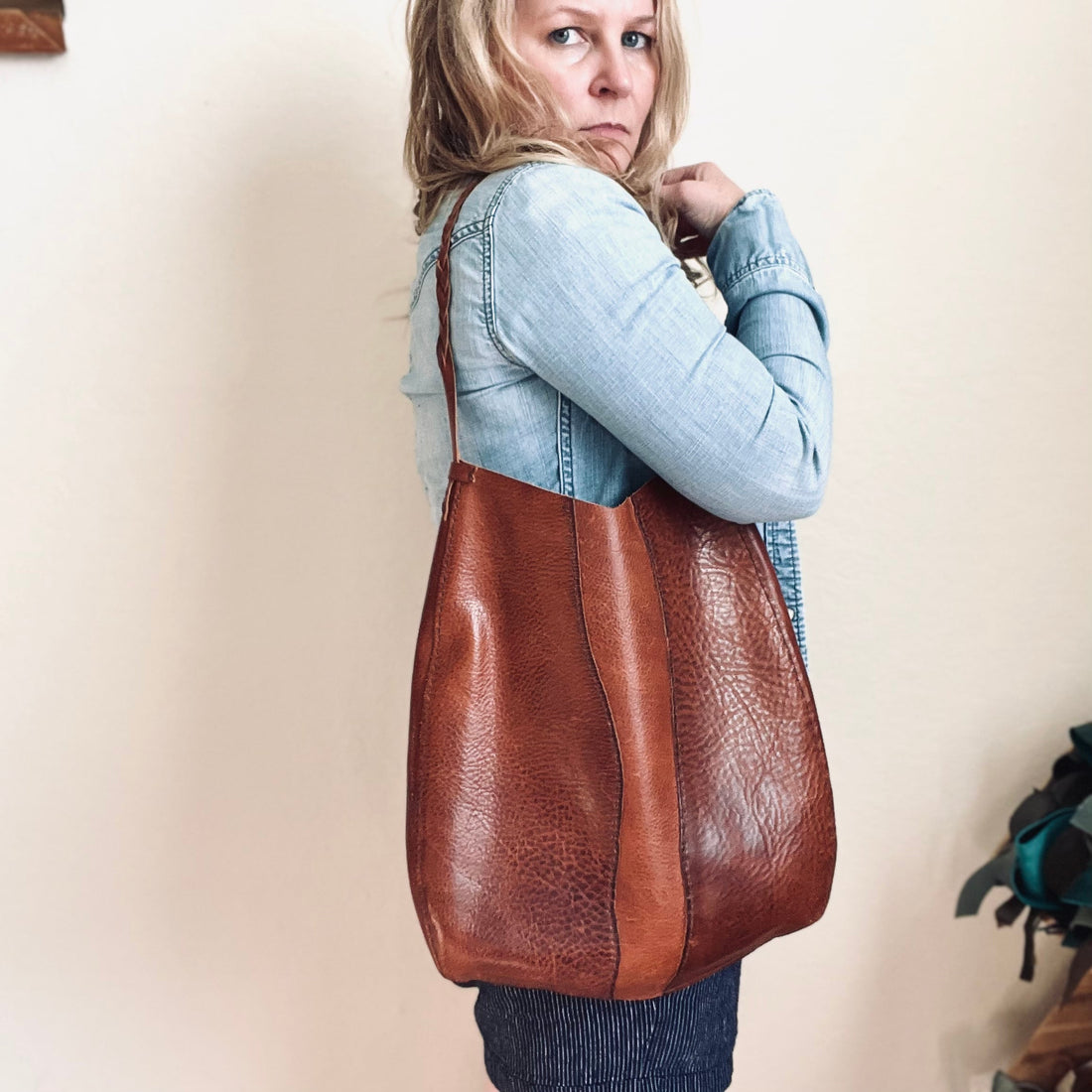 Woman wearing the handcrafted Savannah River Bag by Sondera 1974, made from rich Tuscan-Italian vegetable-tanned leather with raw riverbank-inspired edges, indie artisan style.