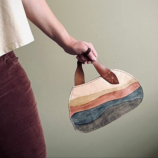 Person holding a colorful handbag against a plain background