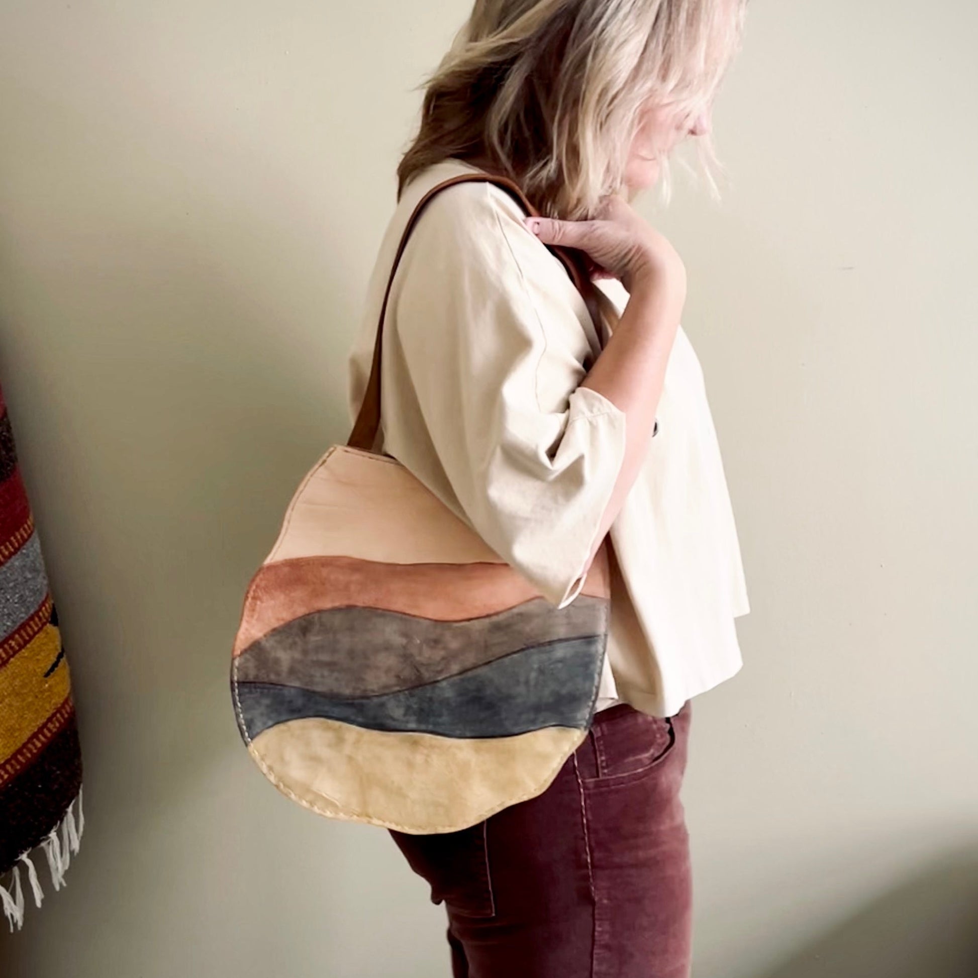 Person holding a multicolored leather bag against a plain background